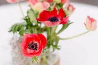 a bold wedding centerpiece of red poppies in a jar wrapped with burlap is a lovely idea for a summer wedding