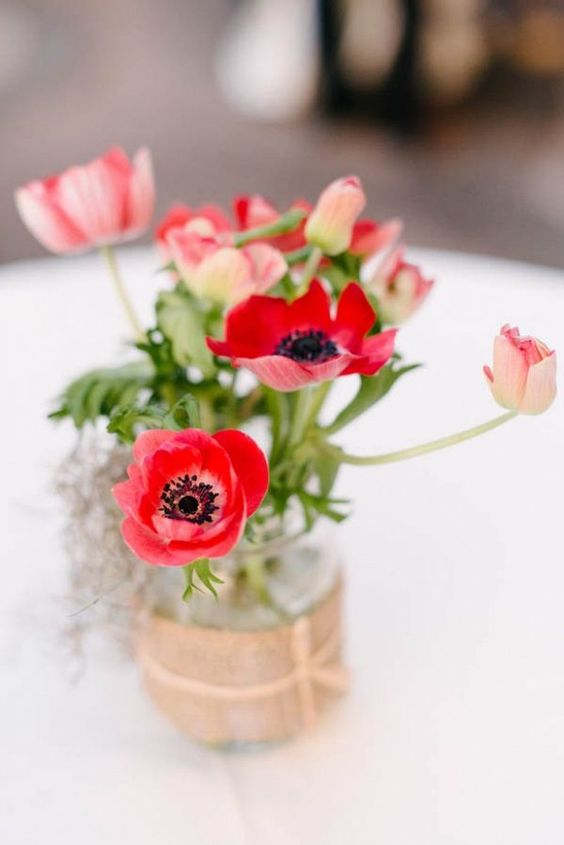 a bold wedding centerpiece of red poppies in a jar wrapped with burlap is a lovely idea for a summer wedding