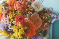 a bold wedding centerpiece of red ranunculus, pink and orange poppies, mimosa, chamomiles and greenery is amazing for a rustic wedding