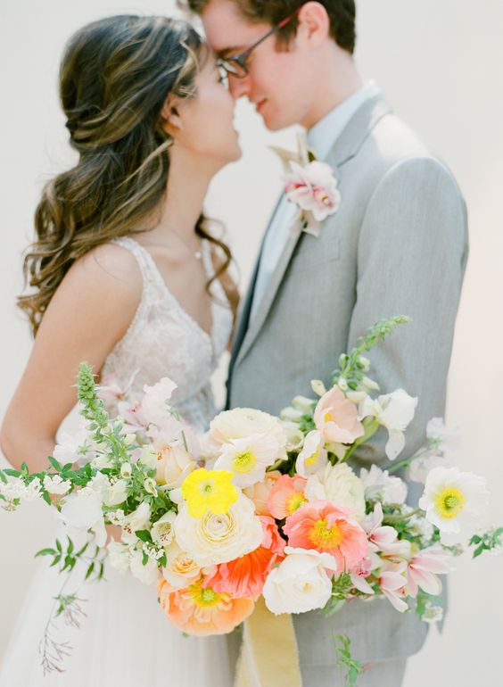 a bright and pretty wedding bouquet of white, coral and yellow poppies, greenery features a cool and very modern shape