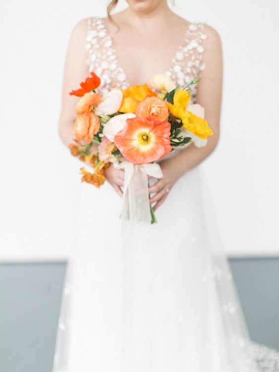 a bright red, orange and yellow poppy wedding bouquets with greenery and some neutral ribbon is amazing as a color accent