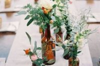 a cluster wedding centerpiece of apothecary bottles, greenery, neutral and pastel blooms is a lovely idea for a spring or summer wedding