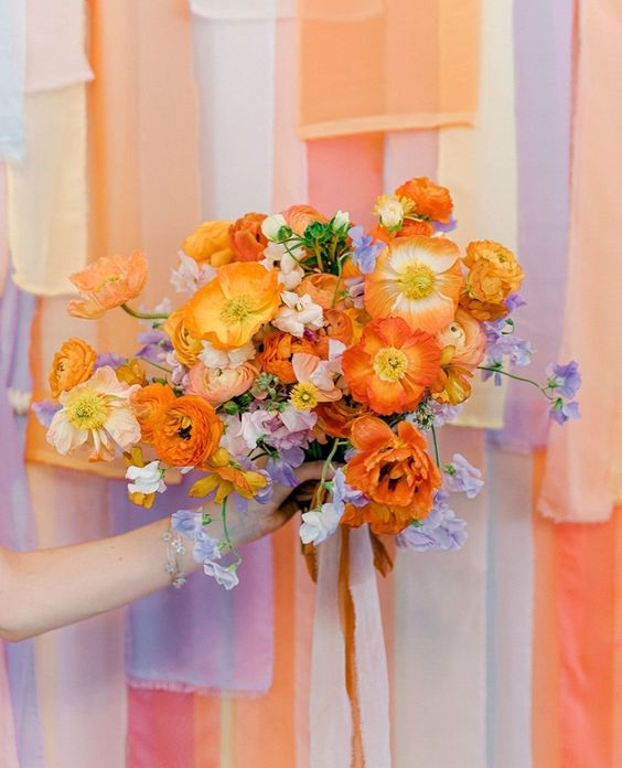 a colorful wedding bouquet of lilac blooms, orange and peachy poppies, orange and yellow peony roses is a bold and unique solution