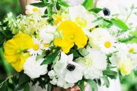 a colorful wedding bouquet of white anemones and dahlias, yellow poppies and chamomiles, greenery for a summer wedding