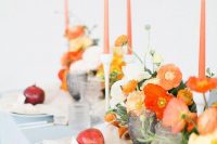 a colorful wedding centerpiece of orange and red poppies, white blooms and greenery and orange candles is great for summer or fall