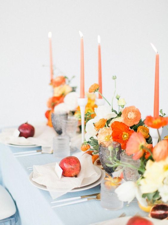 a colorful wedding centerpiece of orange and red poppies, white blooms and greenery and orange candles is great for summer or fall