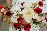 a contrasting wedding bouquet of neutral and red poppies and anemones, blush peonies and burgundy ranunculus plus greenery