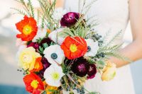 a contrasting wedding bouquet of white and red poppies and anemones, yellow and purple ranunculus, greenery and berries