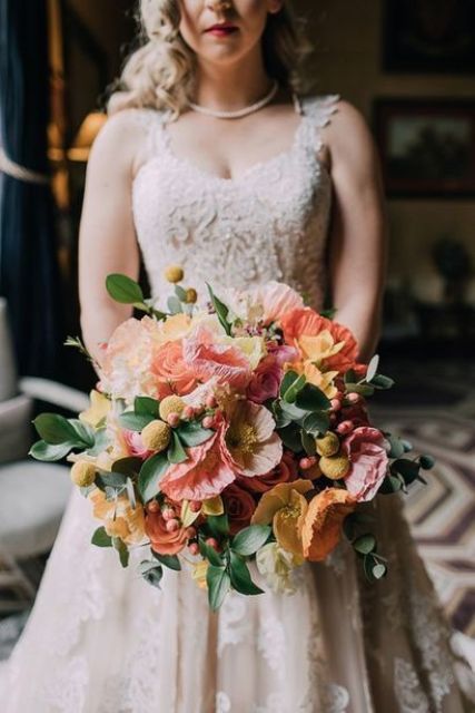 a delicate pastel wedding bouquet of yellow and pink poppies, billy balls and greenery for a spring or pastel summer wedding