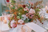 a delicate wedding centerpiece of white and mauve poppies, burgundy and blush blooms, greenery and bold foliage