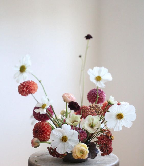 a fab wedding centerpiece of white poppies, pink and orange dahlias and deep purple blooms and yellow ranunculus