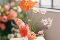 a fantastic wedding centerpiece of a bowl with red, orange and light pink blooms styled as an ikebana is a lovely idea for spring or summer