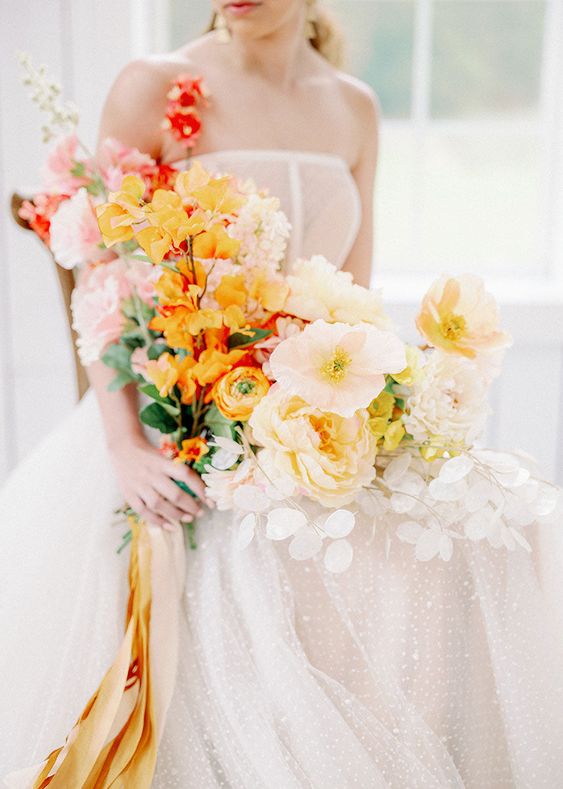 a modern wedding bouquet of yellow and light pink blooms, light pink poppies and yellow ranunculus, yellow and blush ribbon