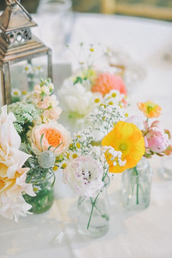 a pastel cluster wedding centerpiece of yellow poppies, blush and white dahlias, peony roses and baby's breath is chic