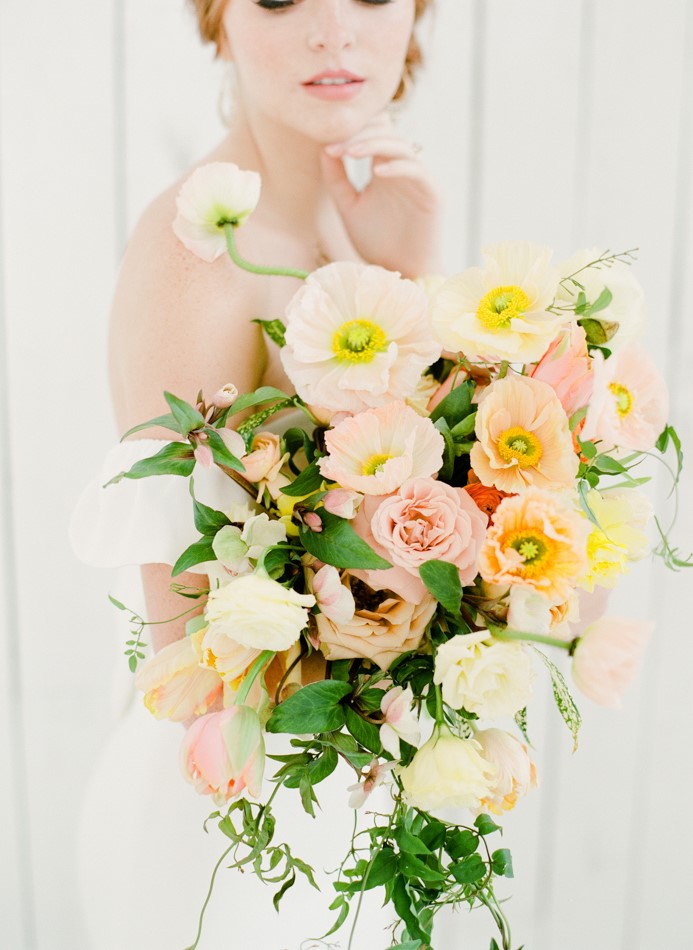 a sophisticated pastel wedding bouquet of light pink roses, light pink and yellow poppies and cascading greenery for a spring birde