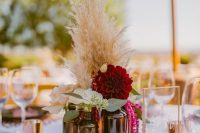 a vineyard wedding centerpiece of a gold trey, apothecary bottles, blush and burgundy blooms, greenery and pampas grass