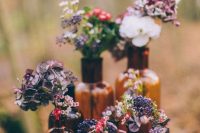 a woodland cluster wedding centerpiece of apothecary bottles and bright blooms will be a nice idea for a fall wedding