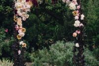 02 a beautiful moody Halloween wedding arch decorated with dark foliage, with neutral, pastel and dark blooms