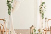 05 a delicate and chic neutral wedding ceremony space with neutral fabric, blooms and greenery, vintage candle lanterns and petals on the floor