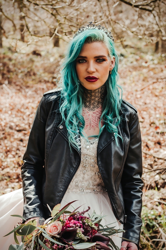 a rock bridal outfit with an A-line wedding dress with an embellished bodice, a black leather jacket, green hair, a celestial tiara and bold tattoos shown off