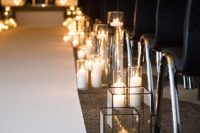 a minimalist wedding aisle with black chairs, clear glass candle lanterns and tall candles in glasses is laconic, chic and bold