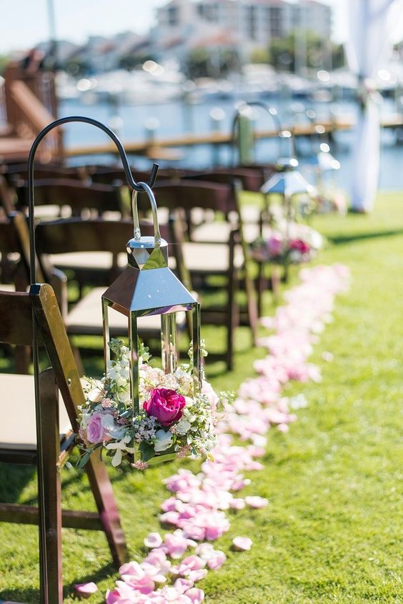 a pretty pink wedding aisle with pink petals on the ground, a polished lantern filled with neutral and pink blooms