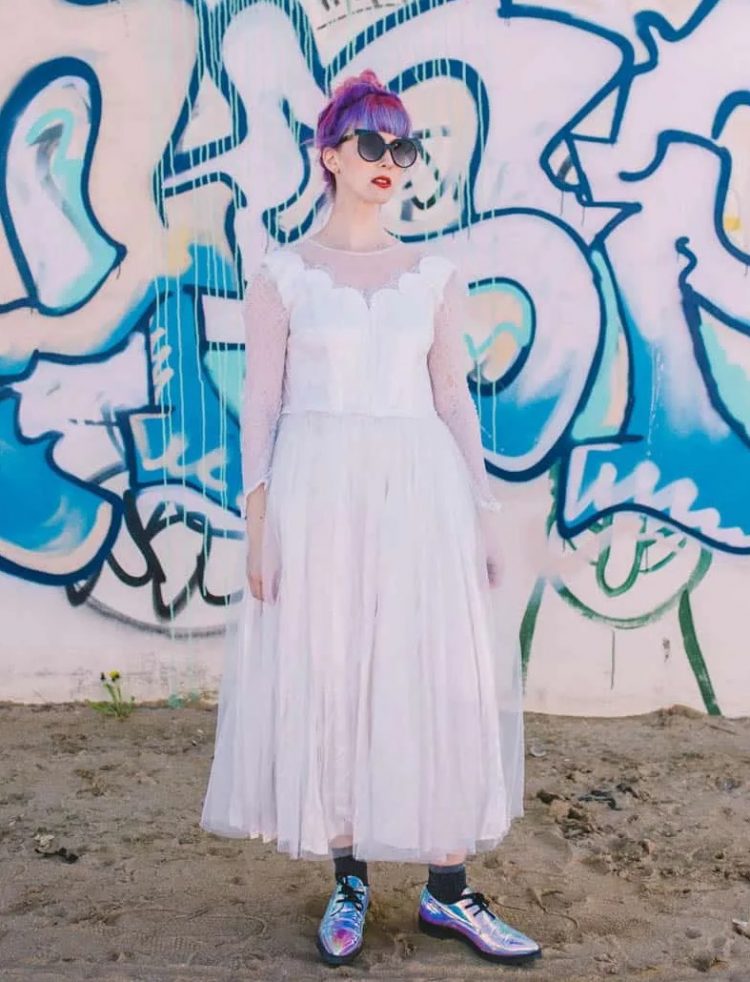 a badass bridal look with anA-line midi wedding dress and sheer sleeves, grey rocks, irridescent shoes and purple to pink hair