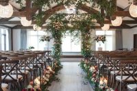 12 a rustic wedding ceremony space with an aisle lined up with blooms and greenery and large candle lanterns, crystal sphere chandeliers and greenery