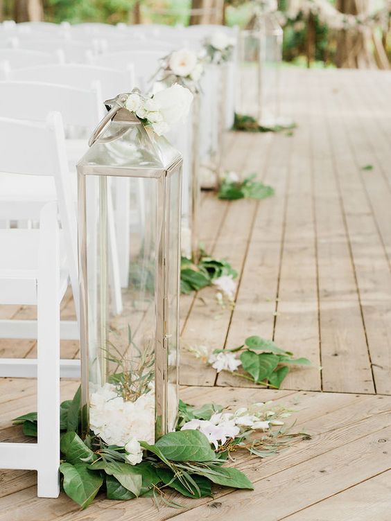 a simple and lovely wedding aisle decorated with super tall lanterns with blooms and greenery around is a great idea