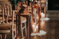 15 a wedding aisle lined up with copper candle lanterns and white petals on the floor, chairs decorated with greenery and white blooms