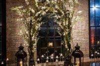 17 a wedding arch composed of blooming branches, giant candle lanterns and floating candles create a unique wedding ceremony space