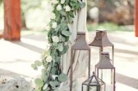 19 a wedding arch with neutral textiles, greenery and white blooms and large metal candle lanterns around is amazing