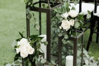 20 a wedding ceremony space done with greenery, black candle lanterns and white blooms on top is a lovely idea for a wedding