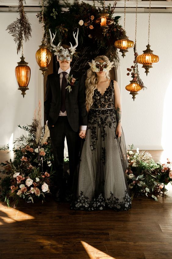 a Halloween wedding altar with greenery, pastel and neutral blooms, pendant lamps on chain is amazing