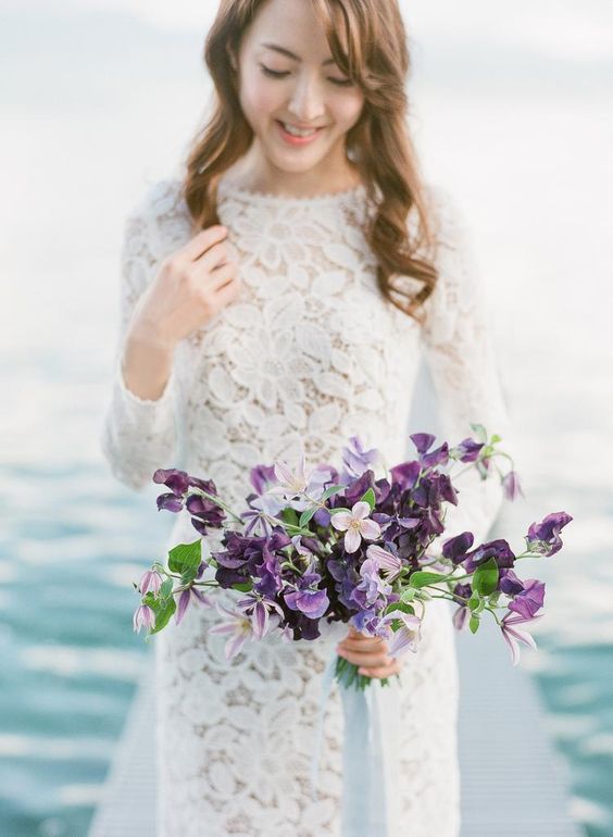 a simple and lovely wedding bouquet with purple and neutral blooms and greenery is a lovely touch of color to a bridal look