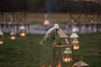 27 wedding aisle decor with metal candle lanterns topped with greenery is a lovely idea for any wedding