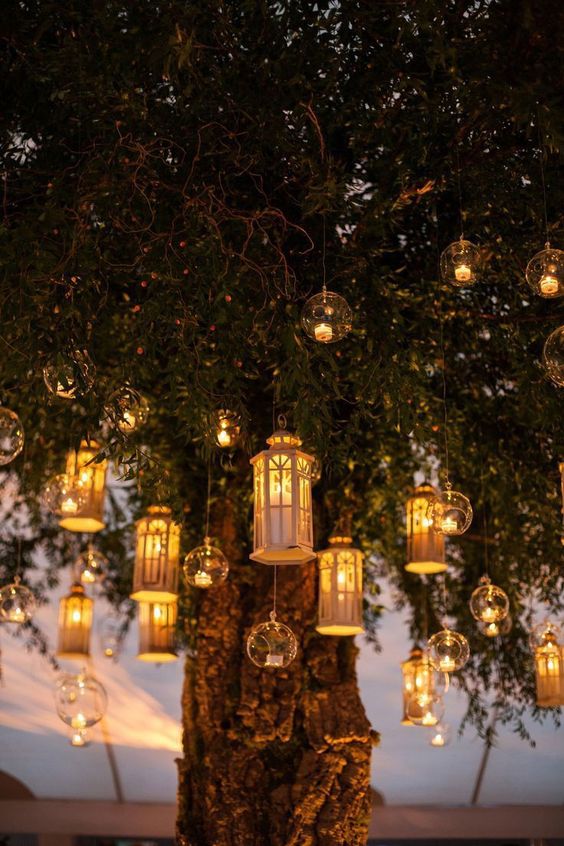 a living tree decorated with hanging candle lanterns and bubbles with little candles is a gorgeous alternative to a wedding arch, for an evening ceremony