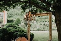 30 a refined and chic outdoor wedding lounge with a peachy daybed, a frame and a vintage chandelier and lanterns with blooms around