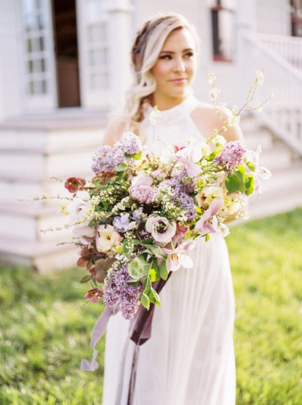 a fantastic lilac and blush wedding bouquet of anemones and lilac blooms, blooming branches and greenery and long ribbon for a spring bride