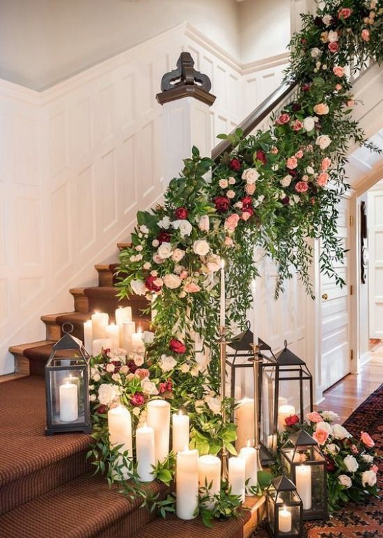 a super lush and gorgeous staircase decorated with greenery, neutral and bold blooms, candles and vintage candleholders for a wedding