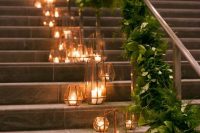 34 a wedding staircase decorated with a lush greenery runner and faceted copper candle lanterns on the steps