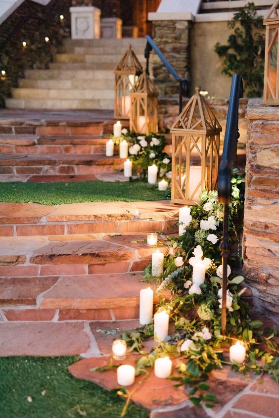 cute rustic wedding decor with greenery and white blooms, white candles and wooden candle lanterns is lovely