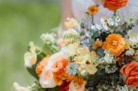 a beautiful and cool wedding bouquet with yellow, burnt orange, blush blooms, greenery and blooming branches