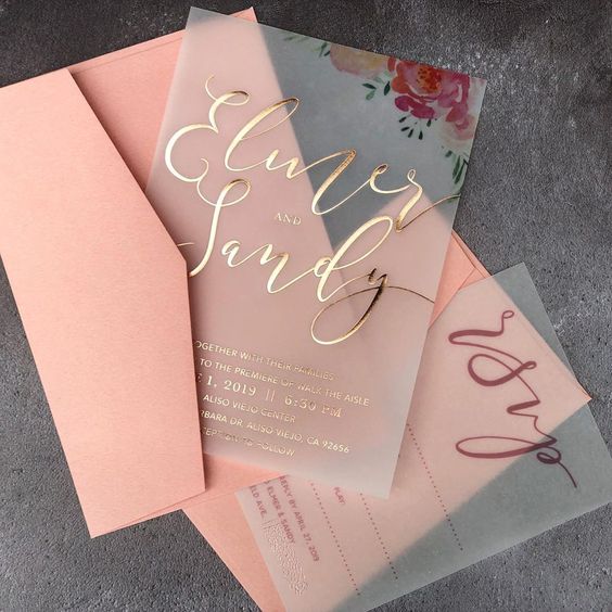 a beautiful and romantic wedding invitation suite with coral envelopes, vellum invites with gold foil calligraphy and floral prints