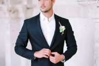 a black groom’s suit with a white shirt and a boutonniere is a timeless and effortlessly chic look