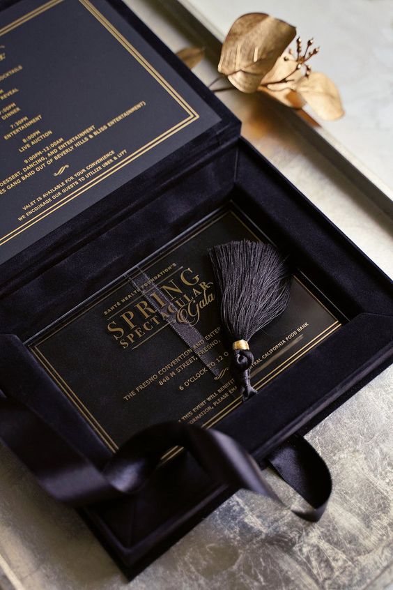 a black velvet wedding invitation box with a clear acrylic invite with gold letters and a tassel is a very chic and lovely idea
