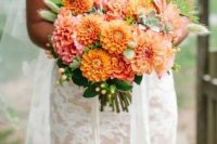 a bold orange and pink wedding bouquet of dahlias, berries and greenery is a lovely idea for a summer or fall wedding