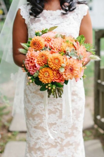 a bold orange and pink wedding bouquet of dahlias, berries and greenery is a lovely idea for a summer or fall wedding