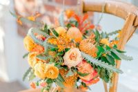 a bold orange wedding bouquet of ranunculus, pincushion proteas, roses, greenery is amazing for summer or fall