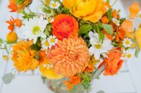 a bold orange wedding bouquet with orange dahlias, ranunculus, chamomiles, greenery is amazing for a rustic wedding